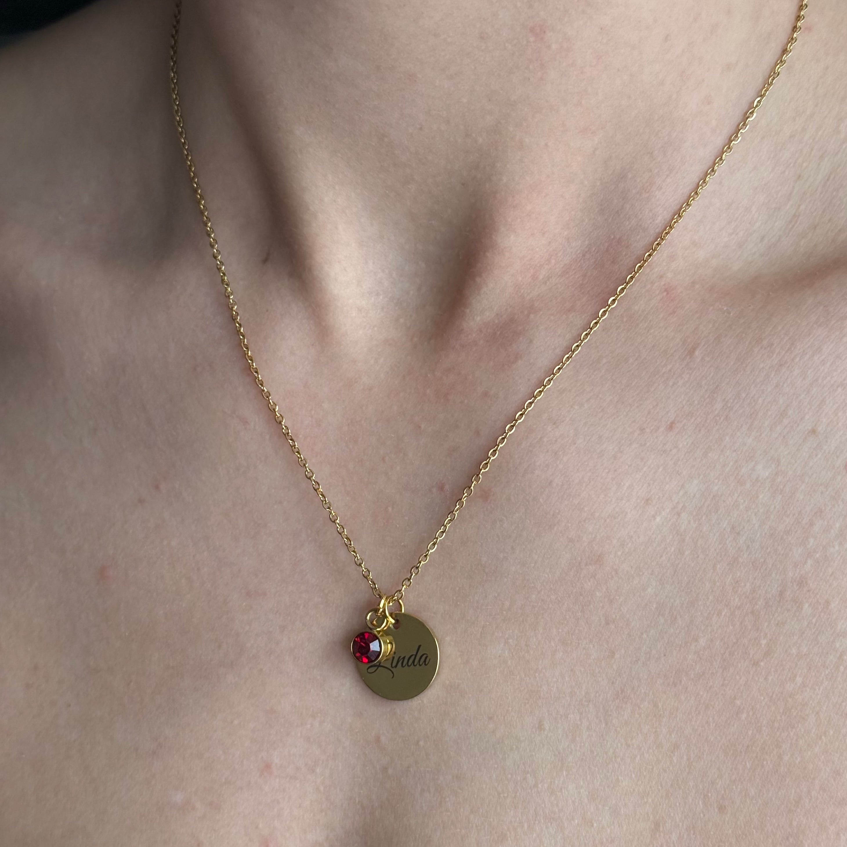 Sieviešu kaklarota zelta krāsā ar sarkanu kristālu un vārda gravējumu